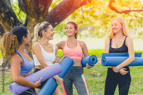 group of healthy girl with yoga mat enjoy talking together relax scene after finish yoga outdoor class.