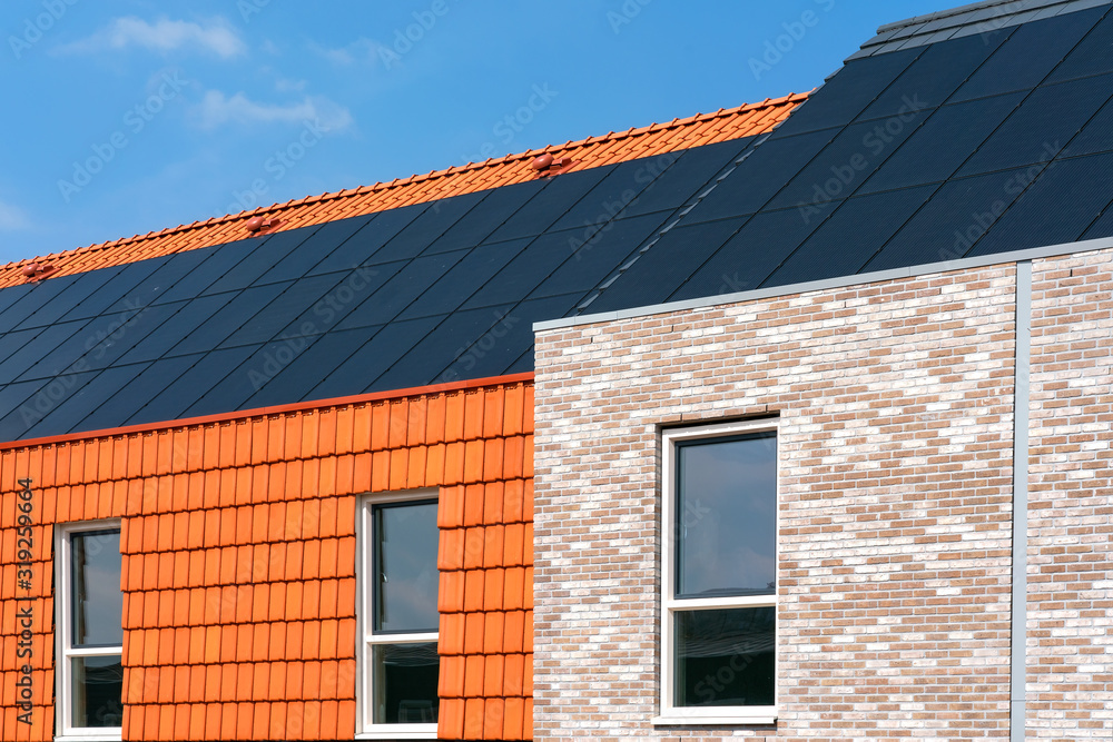 Solar collectors on a roof of a brick facade clad and roof tiles facade clad building. Space for text. Solar collectors on a roof of a brick facade clad and roof tiles facade clad building. Space for text.