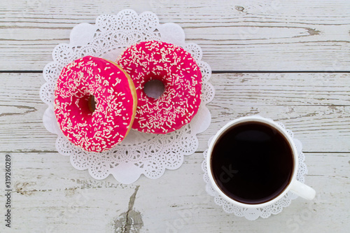Donuts and coffee on a white wood background, top view