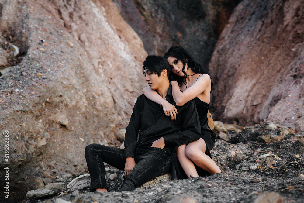 Asian couple in love hugs sitting on the rocks. Love story Asian couple in love hugs sitting on the rocks. Love story