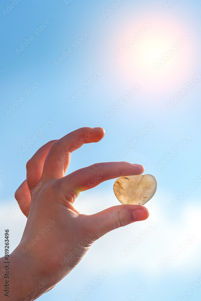 Hand is raising Heart shaped stone with blur sunlight and blue sky background, Valentines day. Hand is raising Heart shaped stone with blur sunlight and blue sky background, Valentines day.