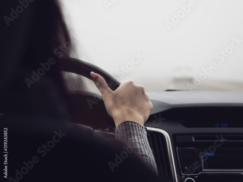 The woman behind the wheel of a car. Poor visibility when driving due to fog. Unfavorable weather conditions for driving
