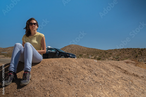 Bilde på lerret Young girl sit in thee desert during a road trop, mojave desert