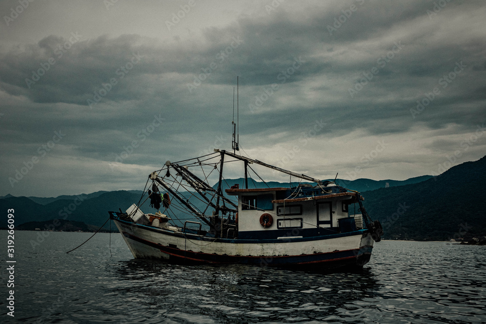 Old boat on the high seas. Cloudy, rainy weather, gray skies and bluish sea.