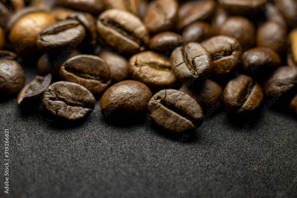 Fototapeta premium Coffee in beans on dark background. Abstract background texture.Coffee beans texture. Food background of coffee beans