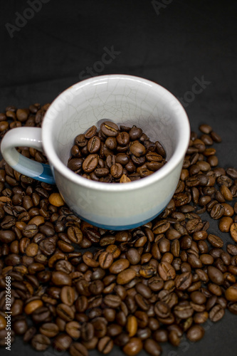 Coffee cup with grains against dark background. Close-up with copy space for your text.