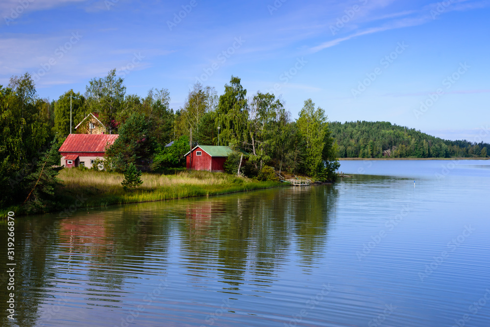 Picturesque lake with wooden houses on the shore, typical nature of Finland.