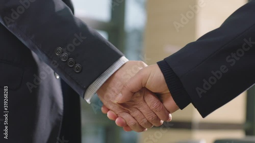 close-up of businessmen shaking hand & greeting in office