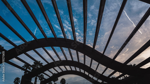 Canvas Print Detail of a pergola wave shaped with a cloudy sky of in the background