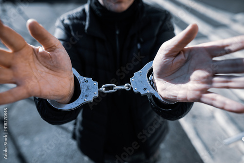 Shallow depth of field (selective focus) image with the handcuffed hands of a man.
