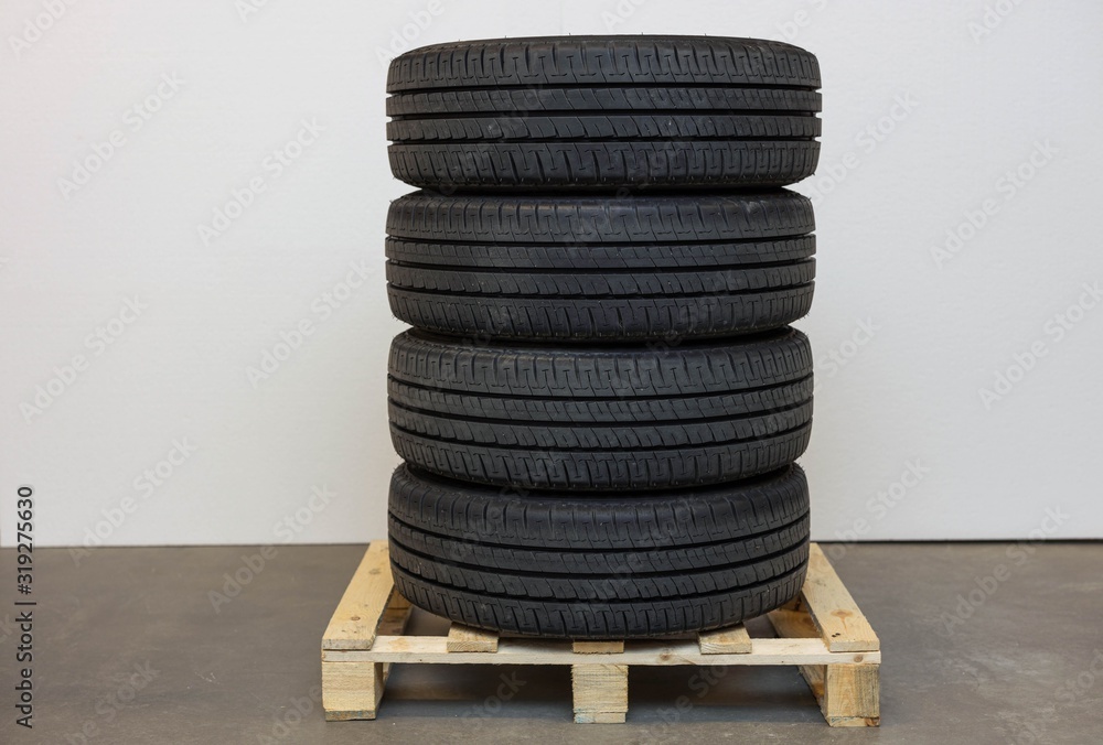 Obraz premium Close up car tyres on wheels storage on a pallet. Car repair box. Transport backgrounds.