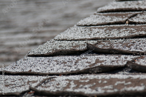 Old worn out asphalt shingles on the roof of a residential home.