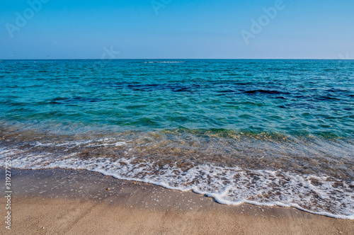 Seascape. Waves running on the sandy shore. Shore of the sea or ocean on a nice day. Vacation and relaxation by the sea. © solidmaks