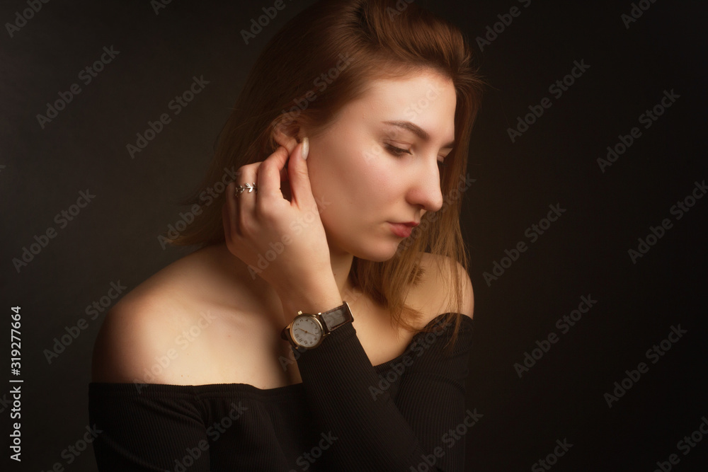 Portrait in the photo Studio of a brown-haired girl, on a black background in black clothes with open shoulders. Short hair. Portrait in the photo Studio of a brown-haired girl, on a black background in black clothes with open shoulders. Short hair.
