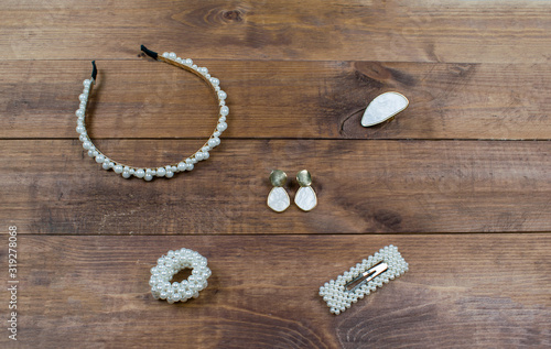 Flatlay set jewelry pearls accessories on wooden brown background. Hair band, ring, earrings, scrunchy and hairpin for hair.