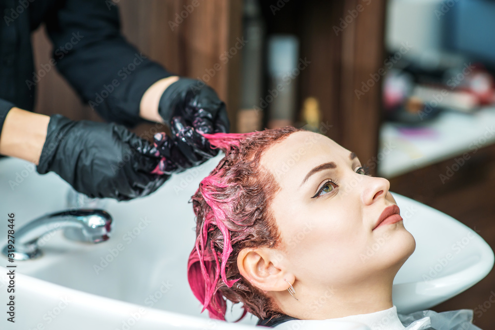 Hairdresser washing colored hair in pink of woman in sink, close up. Hairdresser washing colored hair in pink of woman in sink, close up.