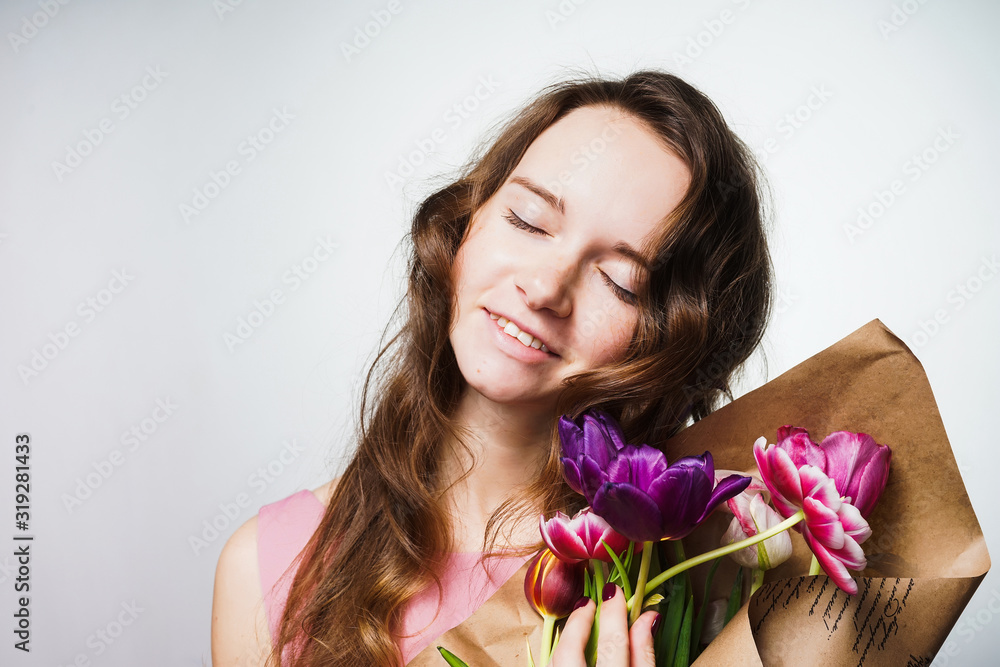 the girl with a bouquet of tulips closed her eyes with pleasure and smiles tenderly the girl with a bouquet of tulips closed her eyes with pleasure and smiles tenderly
