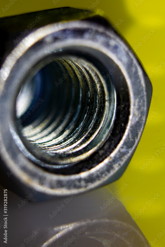 Thread of a hat nut in yellow background light Thread of a hat nut in yellow background light