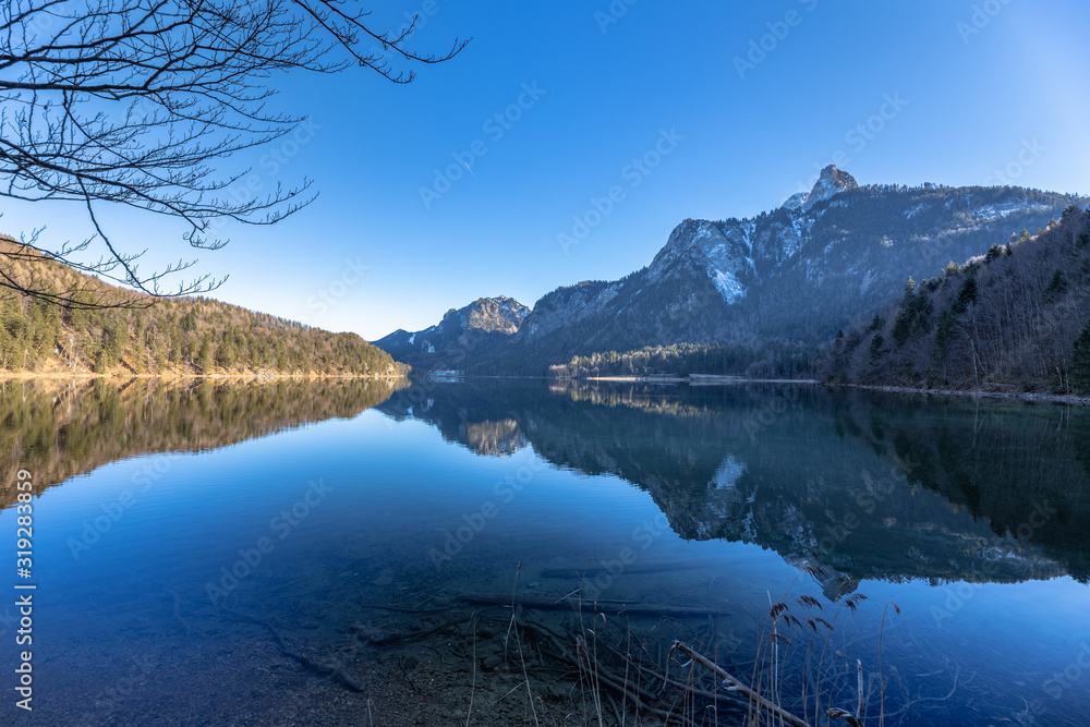 Stunning view of the Alpsee lake in winter with the Neuschwanstein and Bavaria Alps in background
