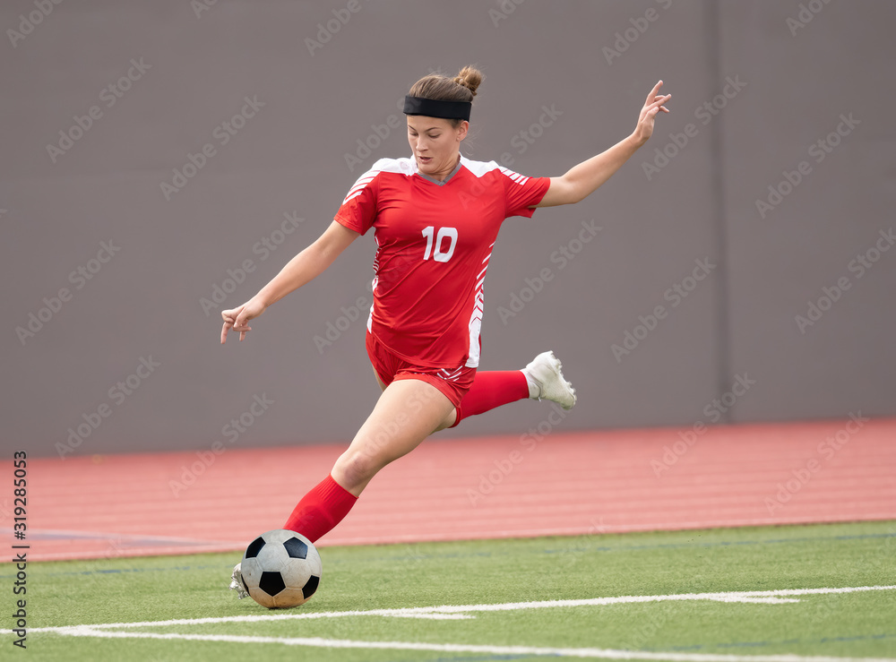 Obraz premium Young athletic girl playing soccer in a game