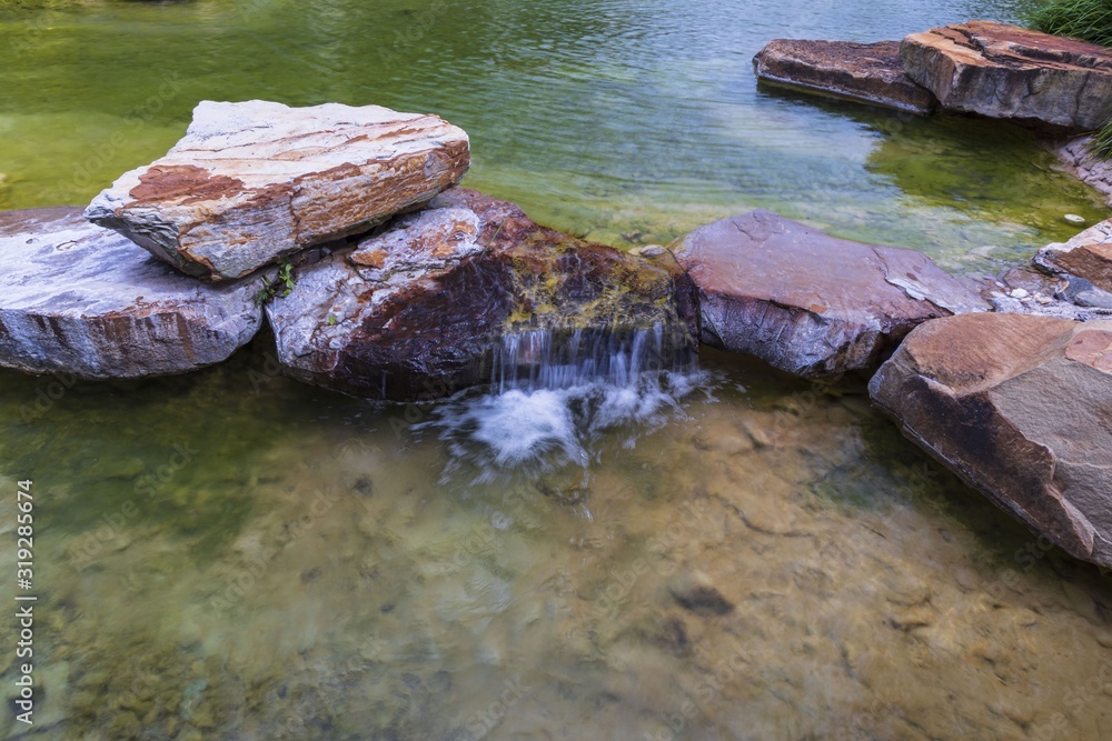 Fototapeta premium Beautiful view of pond decorated with big rocks. Clear water mirror surface effect.