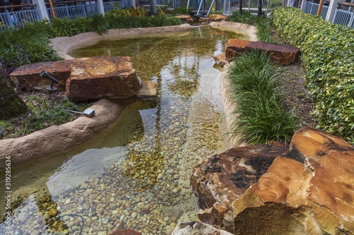 Beautiful view of pond decorated with big rocks. Clear water mirror surface effect.