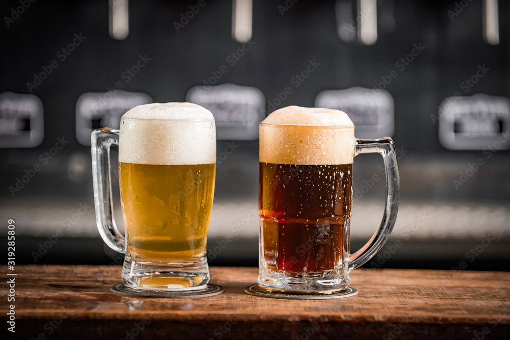 Two mugs full of chopp, one with pilsen chopp and one with dark chop on a rustic table