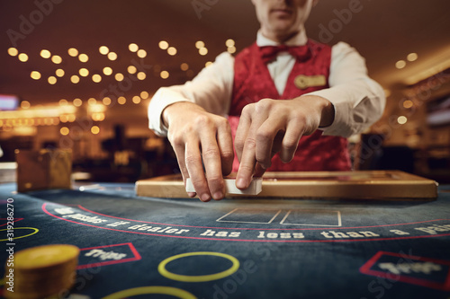 Obraz na plátně Croupier holds poker cards in his hands at a table in a casino.