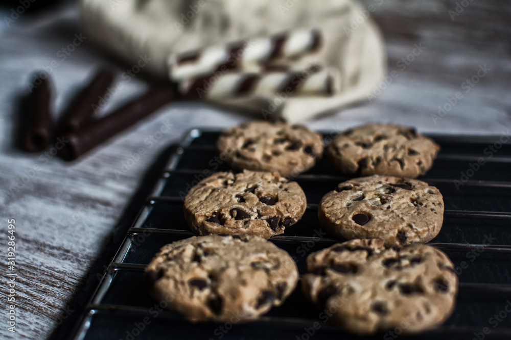 Cake shop. Freshly made chocolate chip cookies on a baking sheet. In the background chocolate waffles. Close up and depth of field Cake shop. Freshly made chocolate chip cookies on a baking sheet. In the background chocolate waffles. Close up and depth of field
