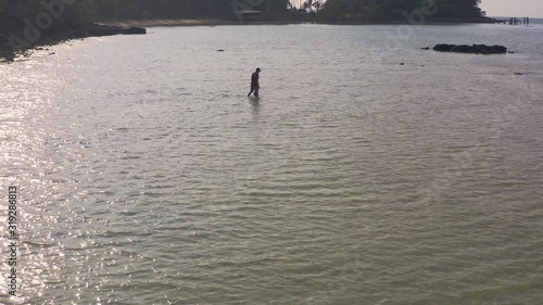 fisherman wading through low tide on his way to collect fish