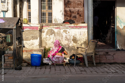 Unidentified Indian woman washing clothes outside her house.