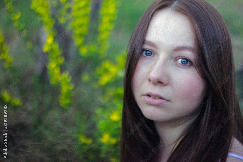 Young girl on the background of wormwood. Photo of a beautiful, mysterious brunette on a background of green grass