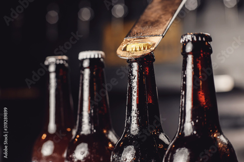 Photos Glass ice cold bottles of beer with opener cap on dark background
