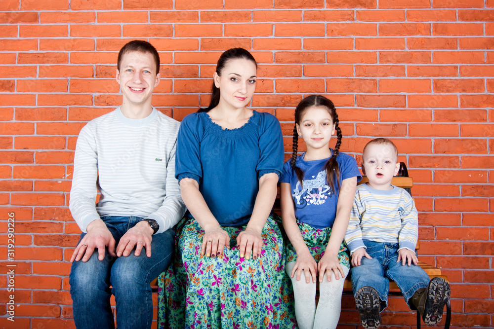 Happy family sit on the bench with hend on knee. Indoor photo shot