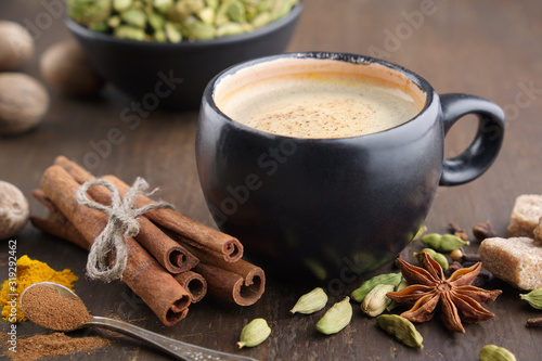 Fototapeta Naklejka Na Ścianę i Meble -  Cup of coffee with spices. Cinnamon sticks, cardamom, allspices, curcuma and anise on wooden table.