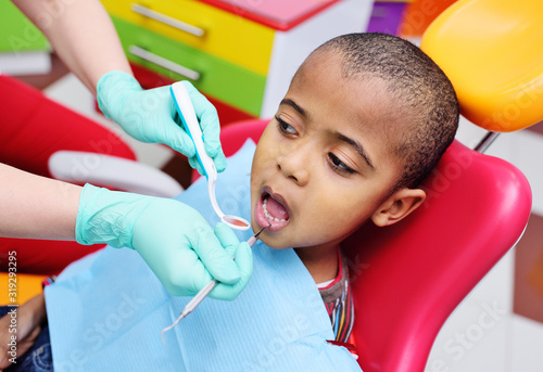 cute black baby boy African American smiling sitting in the dental chair at the examination at the children's dentist.