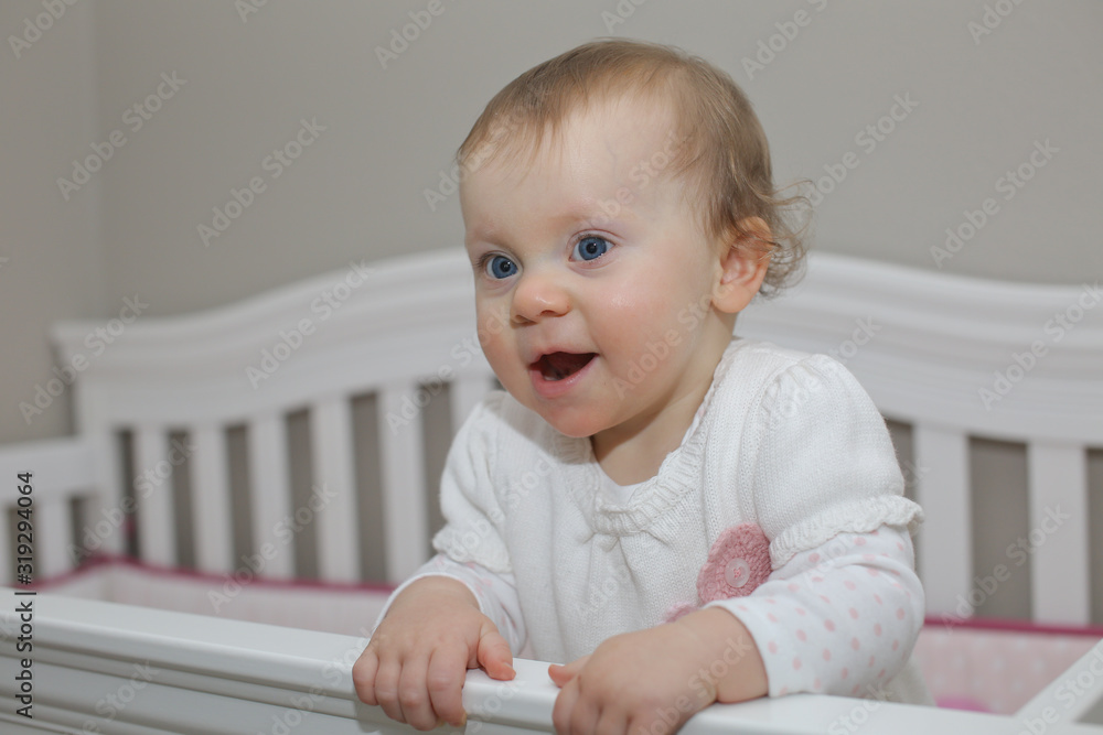 Very Cute 10 Month Old Baby Girl with Big Blue Eyes Playing in the White Crib Very Cute 10 Month Old Baby Girl with Big Blue Eyes Playing in the White Crib