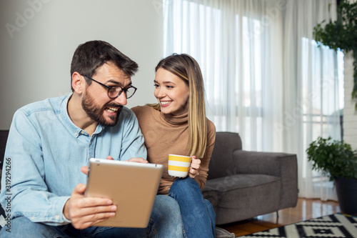Couple using tablet while sitting at sofa in apartment