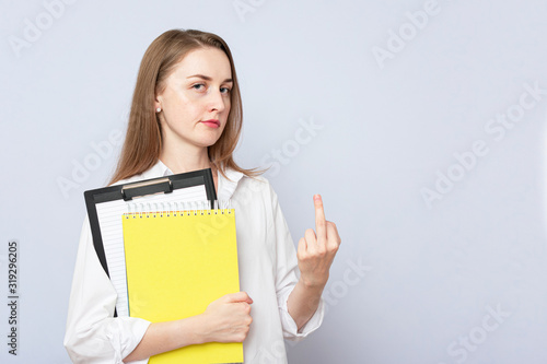 Student woman showing middle finger doing fuck you bad expression, provocation and rude attitude, portrait, gray background photo