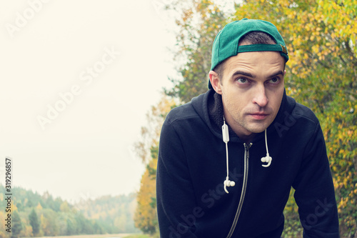 Guy on a morning jog in the autumn Park, man listening to music with headphones, portrait © Анастасия Семашко