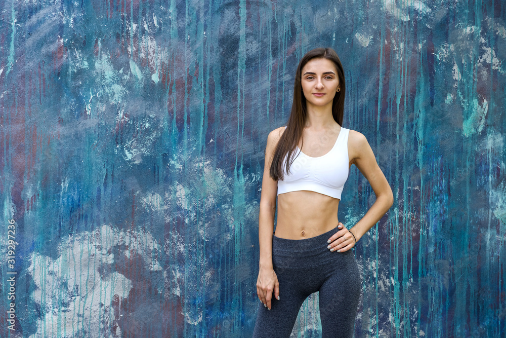 Fototapeta premium Portrait of slim and sportive woman on abstract background. Sport and health