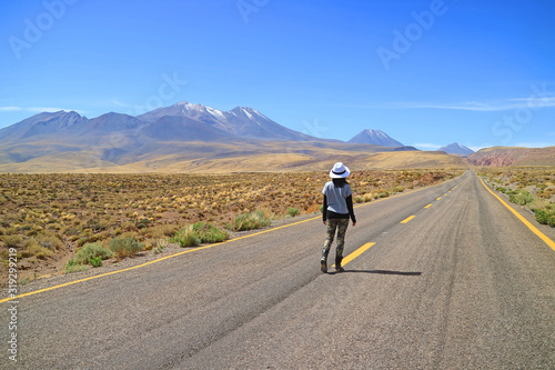 Female Traveler walking on the empty road of Atacama desert in northern Chile
