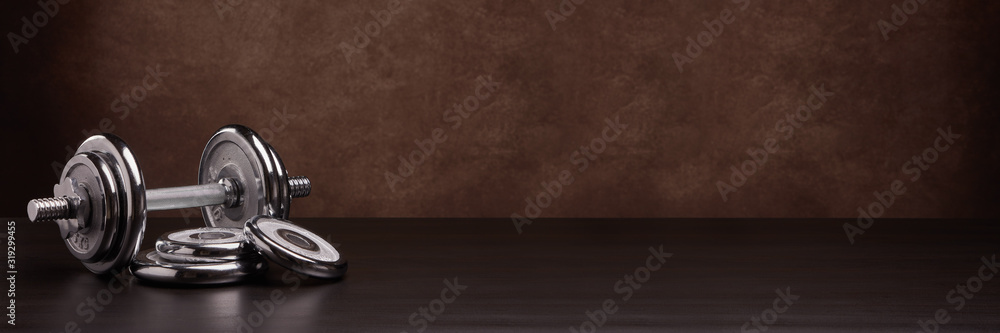 Steel dumbbell and weights on brown background. Fitness, sport, healthy lifestyle concept. Extra wide panorama banner background - obrazy, fototapety, plakaty 