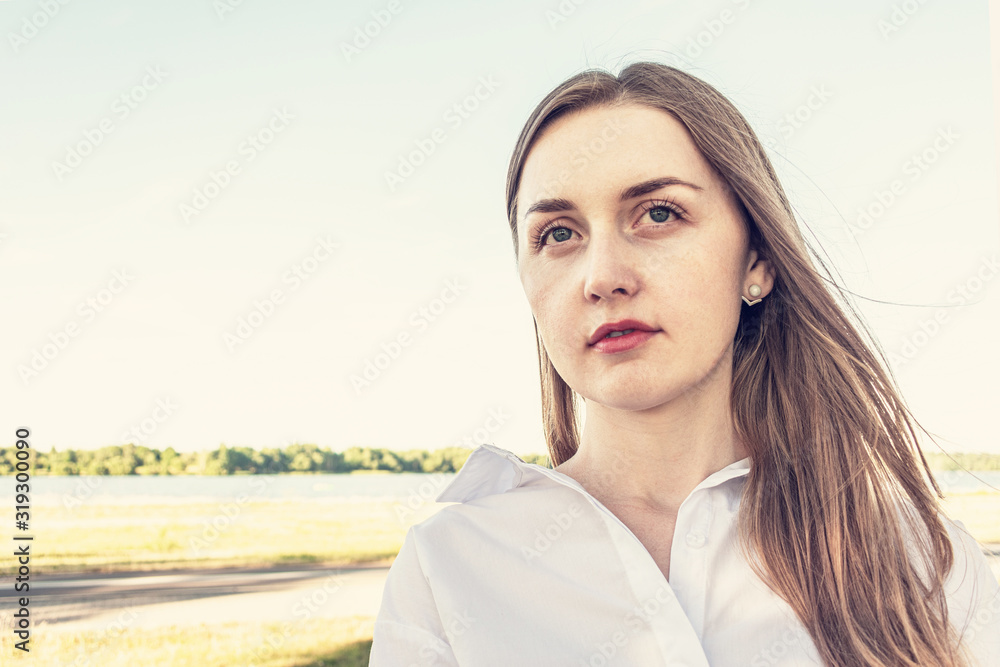 Beautiful young girl looks into the distance against the blue sky, portrait, copy space, toned Beautiful young girl looks into the distance against the blue sky, portrait, copy space, toned