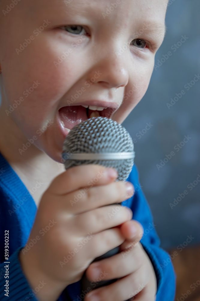 charming kid sings into microphone and opens her mouth wide with milk teeth dropped out. charming kid sings into microphone and opens her mouth wide with milk teeth dropped out.