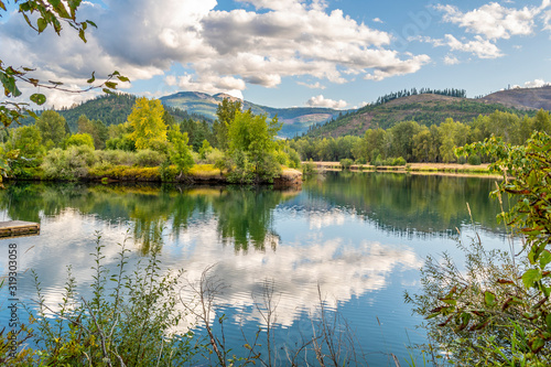 Fototapeta Naklejka Na Ścianę i Meble -  A serene partly cloudy late summer day on the Coeur d'Alene River in the Silver Valley area of North Idaho, USA