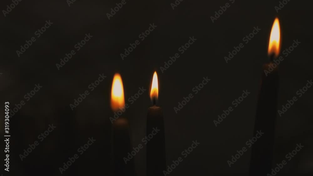 Three candles burning on a black background on the day of a religious festival Three candles burning on a black background on the day of a religious festival