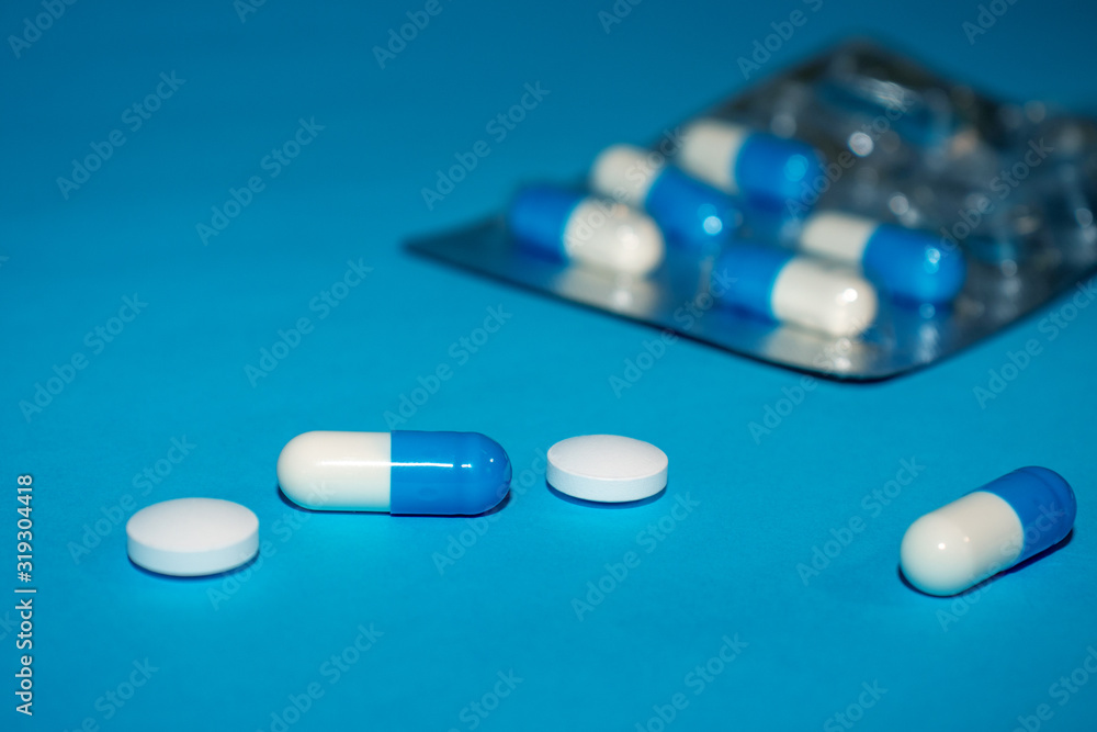 Pharmaceutical medicine tablets, pills and capsules in blister on blue background. Medicine concept.
