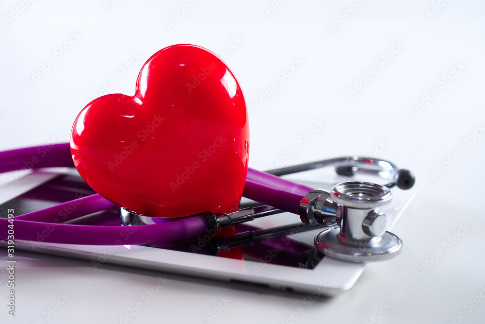 Medical stethoscope and a red heart and tablet on white background. Technology concepts and treatment of heart disease. Medical stethoscope and a red heart and tablet on white background. Technology concepts and treatment of heart disease.