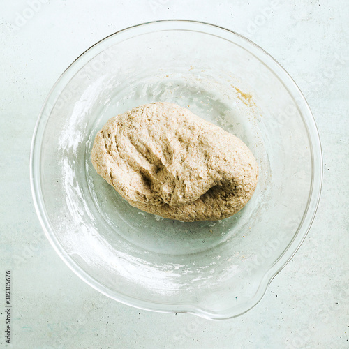 cooking dough for pita bread on a table in a glass bowl, rolling pin and knife photo